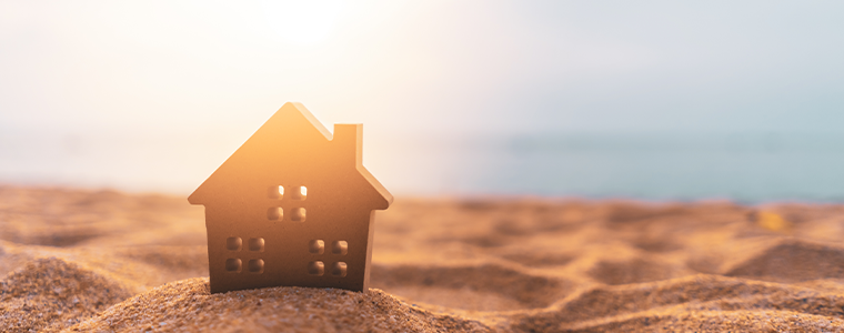 Small home model on sunset beach sand texture background.