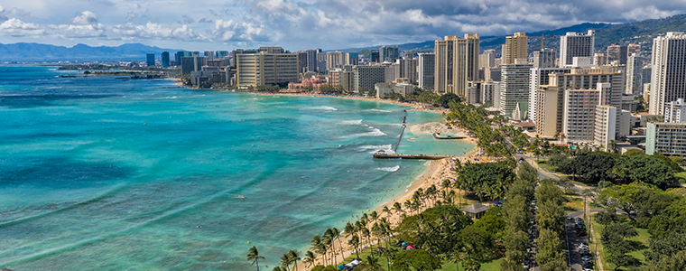 Aerial view of Waikiki skyline neighborhood and city park next to Queens Beach in Honolulu, Hawaii