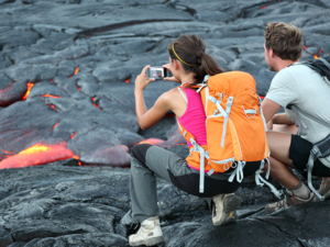 Tourists taking photo of flowing lava from Kilauea volcano around Hawaii volcanoes national park, USA.