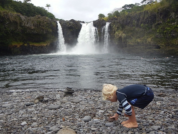 Boy picks up rocks at Wai'ale Falls in Hawaii