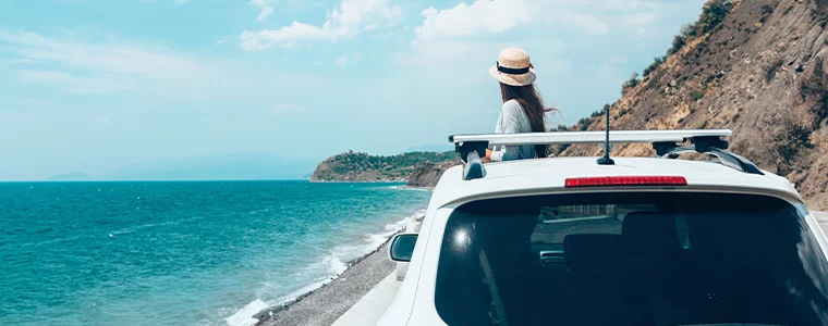 Rear view of lady in car over sea view on summer roadtrip to the beach