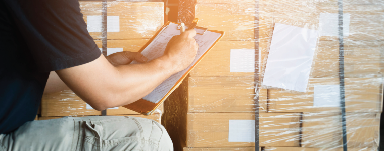 man taking inventory of warehouse boxes